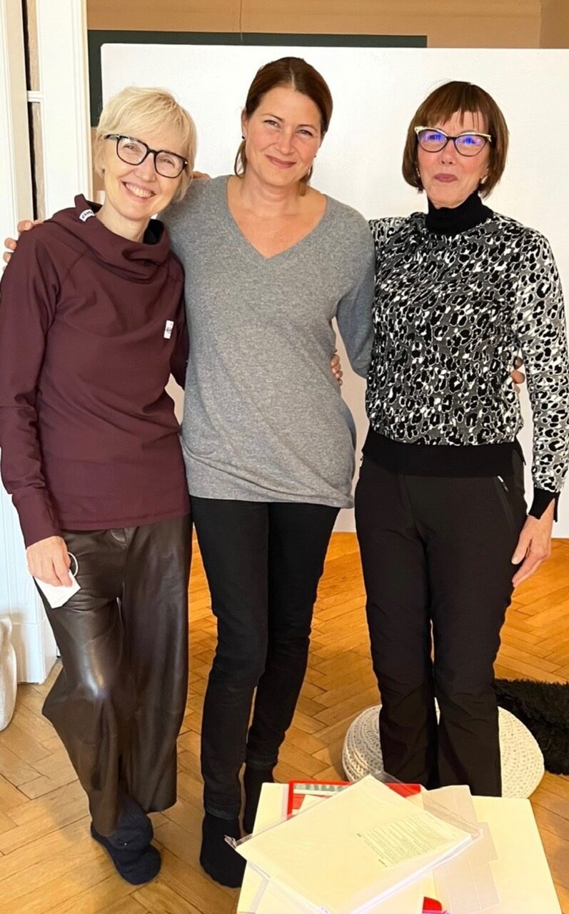 Drei Frauen stehen Arm in Arm in einem Kursraum des montessori labors