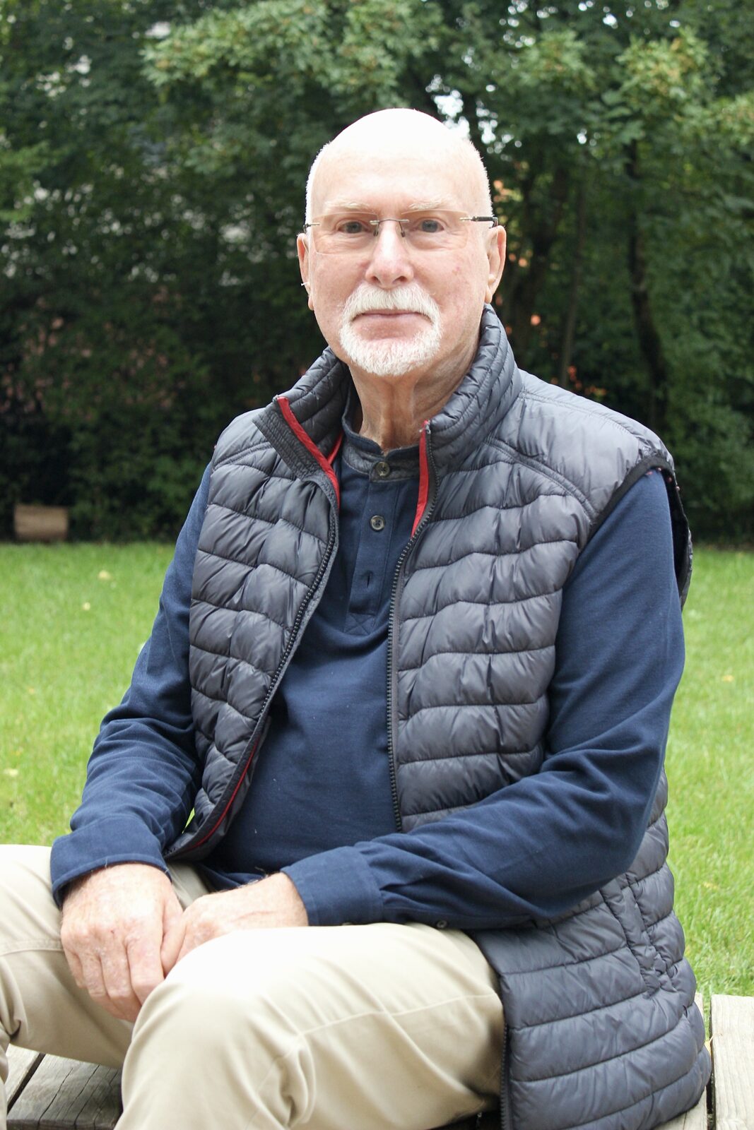 Rainer Völkel sitzt auf einer Bank in einem Garten
